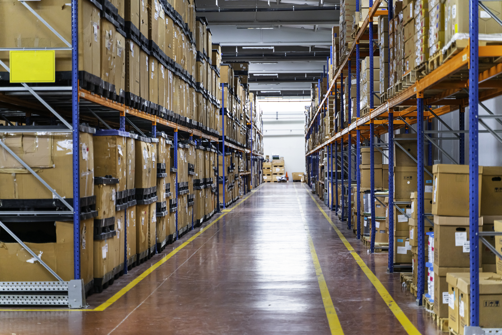 Spacious Warehouse Interior With Tall Racking Systems Displaying Stacked Pallets in Business Environment. Interior of a large warehouse features high racking systems filled with neatly stacked pallet.